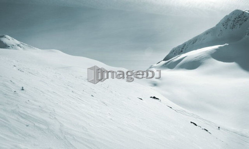 Skier dwarfed by mountain; Canada, British Columbia, Rogers Pass