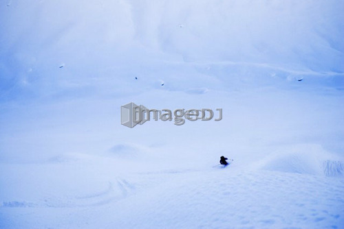 Skier dwarfed by mountain; Canada, British Columbia, Rogers Pass