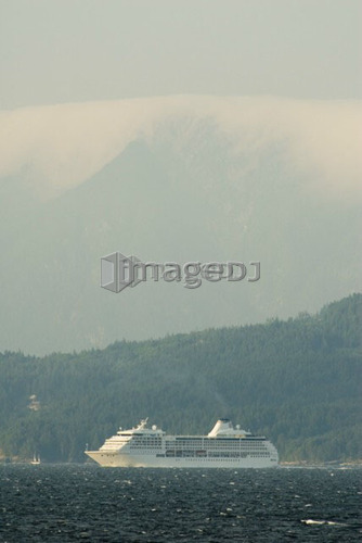 A Cruise ship passing below a large mountain; Canada, British Columbia, Nanaimo