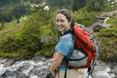 Woman prepares to cross a small alpine creek; USA, Washington, Olympic National Park.
