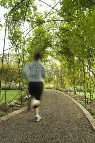 Woman (20-25) jogging through a garden; Canada, British Columbia, Victoria