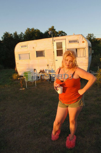 Woman in slippers beside run-down trailer; Canada, Saskatchewan, Cypress Hills