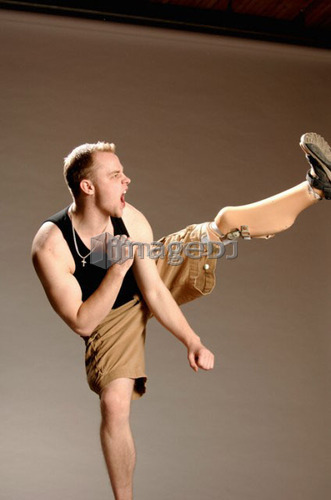Portrait of young man (21 years of age) doing high kick with his prosthesis; Canada, Saskatchewan, Regina