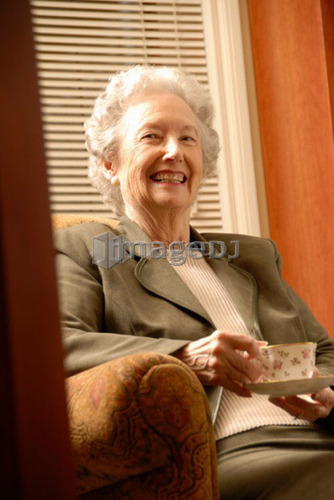 Senior Woman in Library with Tea; Canada, Saskatchewan, Regina