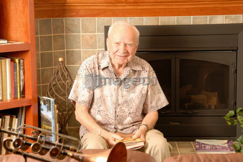 Senior male sitting fireplace; Canada, Saskatchewan, Regina