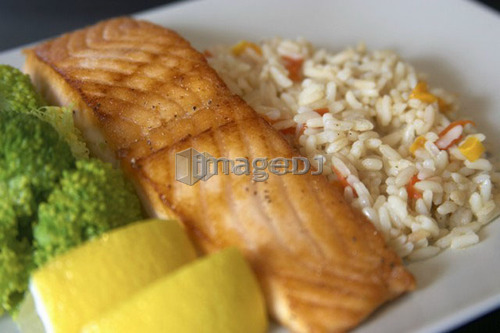 Dinner plate of salmon with rice and broccoli garnished with lemon wedges, Canada, Ontario
