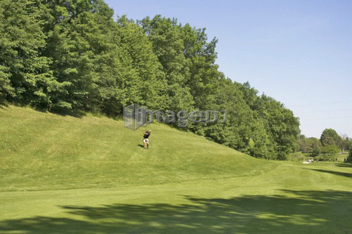 Golfer swinging from the rough of a golf course, Canada, Ontario, Burlington