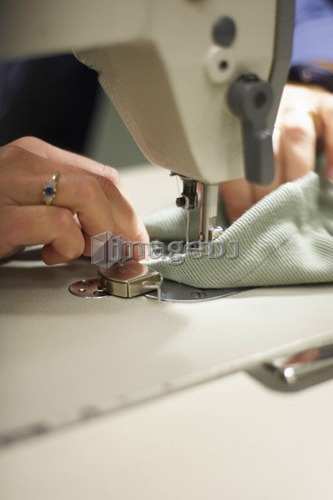 Detail of hands sewing fabric on a sewing machine, Canada, Ontario
