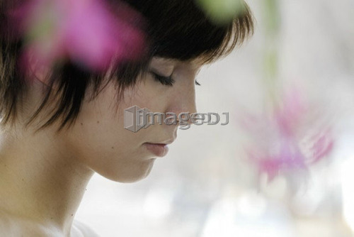 Cactus flower blurred in foregroundof portrait of young woman, Canada, Manitoba,  Brandon