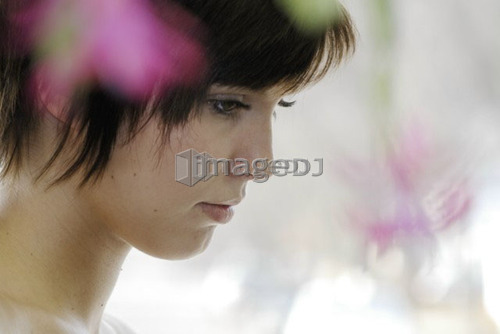 Cactus flower blurred in foreground of portrait of young woman, Canada, Manitoba, Brandon