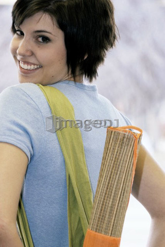 Young woman carrying bamboo mat and cloth shopping bag made with hemp fibres, Canada, Manitoba, Brandon