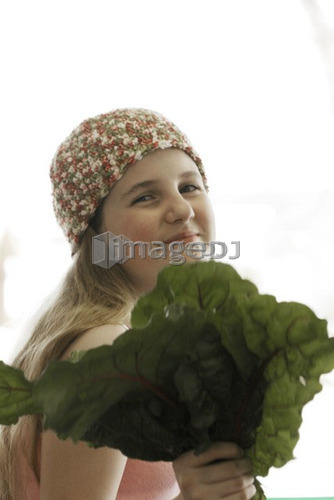 Pre-teen girl holding organic red chard, wearing shirt made with hemp fibre, Canada, Manitoba, Brandon