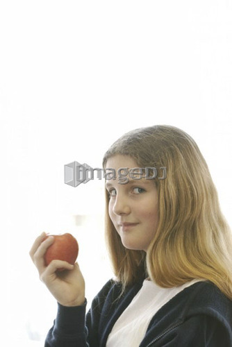 Pre-teen girl eating organic apple, wearing hoodie made with hemp fibre, Canada, Manitoba, Brandon