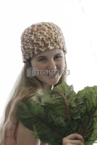 Pre-teen girl holding organic red chard, wearing shirt made with hemp fibre, Canada, Manitoba, Brandon