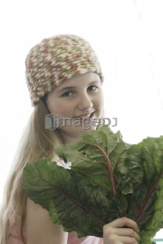 Pre-teen girl holding organic red chard, wearing shirt made with hemp fibre, Canada, Manitoba, Brandon