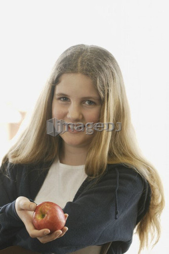 Pre-teen girl holding organic apple, wearing hoodie made with hemp fibre, Canada, Manitoba, Brandon
