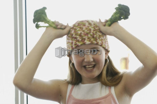 Pre-teen girl holding organic broccoli, wearing shirt made with hemp fibre, Canada, Manitoba, Brandon