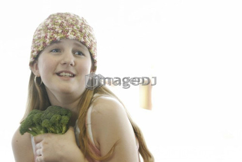 Pre-teen girl holding organic broccolli, wearing shirt made with hemp fibre, Canada, Manitoba, Brandon