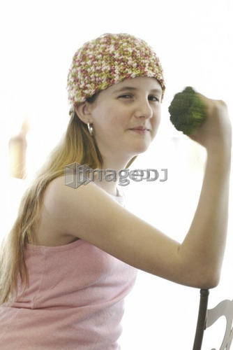 Pre-teen girl holding organic broccoli like a hand weight, wearing shirt made with hemp fibre, Canada, Manitoba, Brandon