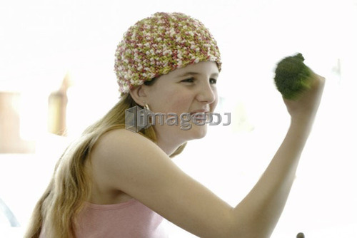 Pre-teen girl holding organic broccoli like a hand weight, wearing shirt made with hemp fibre, Canada, Manitoba, Brandon