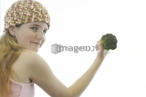 Pre-teen girl holding organic broccoli like a hand weight, wearing shirt made with hemp fibre, Canada, Manitoba, Brandon