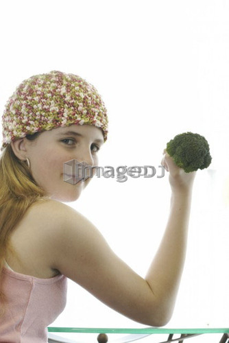 Pre-teen girl holding organic broccoli like a hand weight, wearing shirt made with hemp fibre, Canada, Manitoba, Brandon