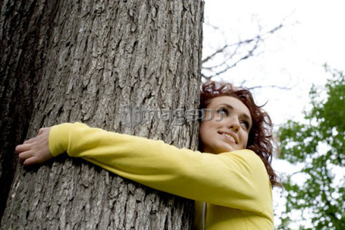 Young woman with arms around tree, Munson Park, Winnipeg, Canada