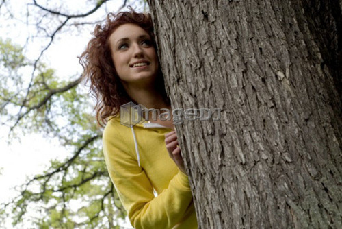 Young looks out from behind large tree, Munson Park, Winnipeg, Canada