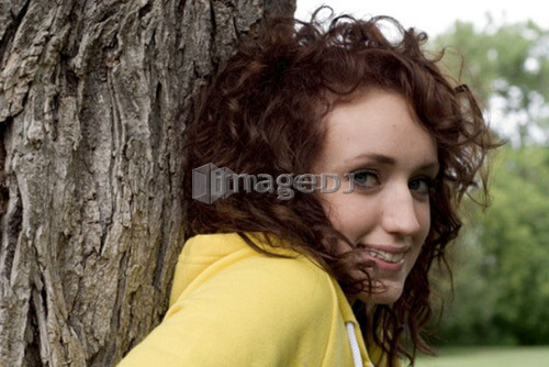 Young woman leaning against large tree, Munson Park, Winnipeg, Canada