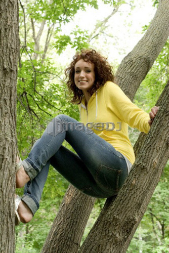 Young woman perched branches of tree, Munson Park, Winnipeg, Canada