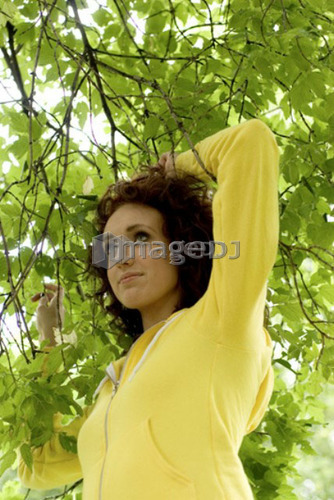 Woman under the green leaves and branch of tree, Munson Park, Winnipeg, Canada