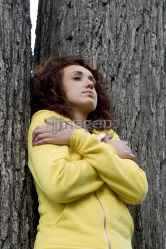 Woman with eyes closed leans against trunk of tree, Munson Park, Winnipeg, Canada