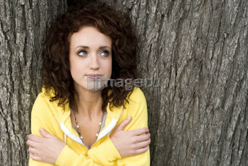 Woman leans against large trunk of tree, Munson Park, Winnipeg, Canada