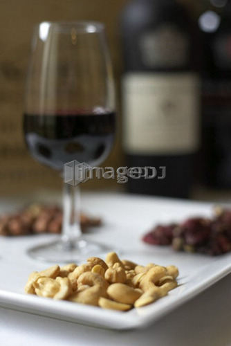 Glass of red wine presented on a platter with a variety of nuts