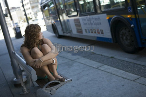 Female, 17, watches for bus at bus stop, Broadway St., Vancouver, BC