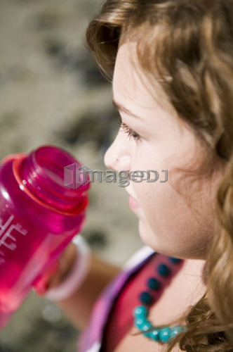 Female, 17, drinking from water bottle while at the beach, English Bay, Vancouver, BC