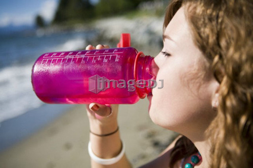Female, 17, drinking from water bottle while at the beach, English Bay, Vancouver, BC