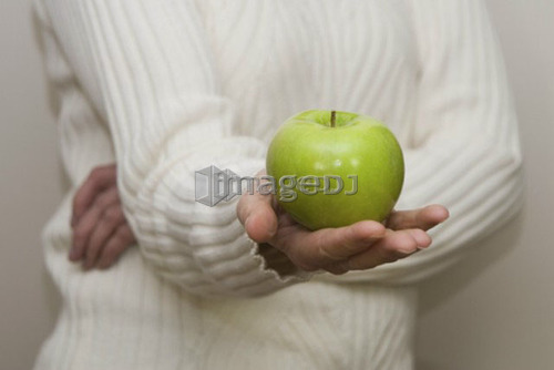 Woman holding organic apple out in front of her