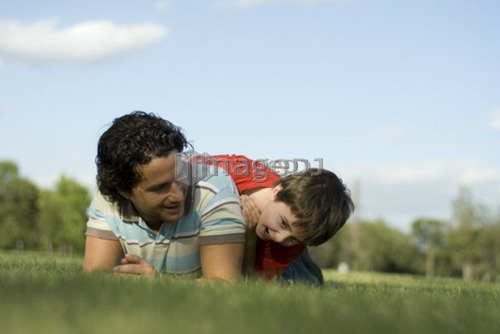 Six year old boy frolics on grass with father, Assiniboine Park, Winnipeg, Canada