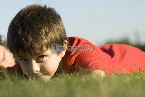 Six year old boy looks up from laying on grass, Assiniboine Park, Winnipeg, Canada