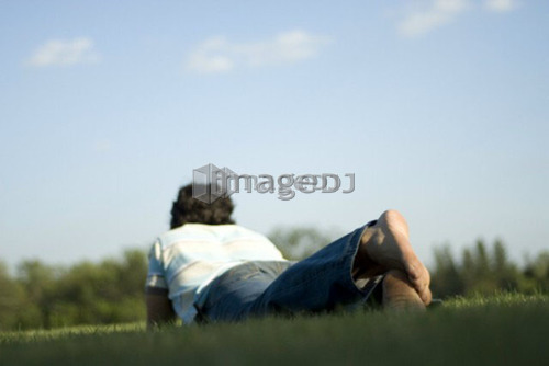 Man lying on grass with feet toward camera, Assiniboine Park, Winnipeg, Canada