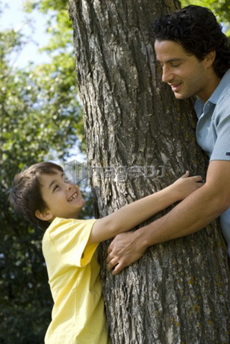 Six year old boy and father hugging tree, Assiniboine Park, Winnipeg, Canada