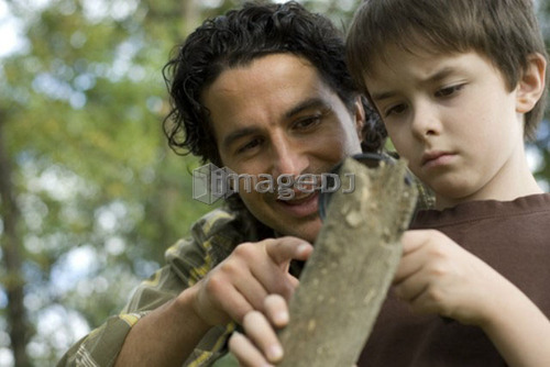 Six year old boy and father look through magnifying glass at rooting log, Assiniboine Park, Winnipeg, Canada