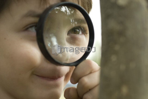 Six year old boy looking through magnifying glass, Winnipeg, Canada