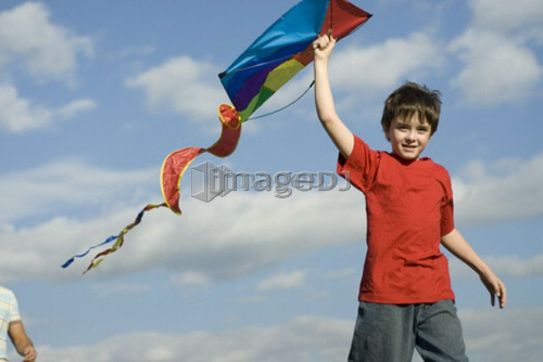 Six year old boy holding kite over head, Assiniboine Park, Winnipeg, Canada