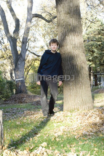 Teen boy leaning on tree, Winnipeg, Canada
