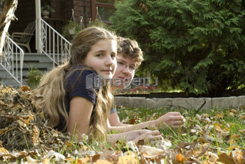 Teen brother and sister lying in leaves viewed from the side, Winnipeg, Canada