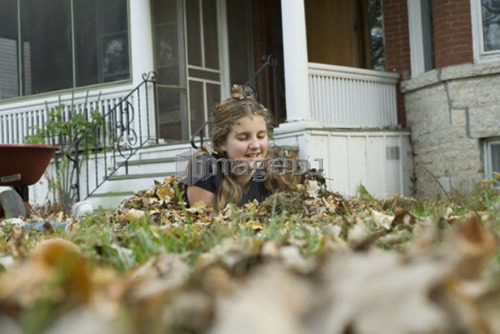 Teen girl covered in leaves, Winnipeg, Canada