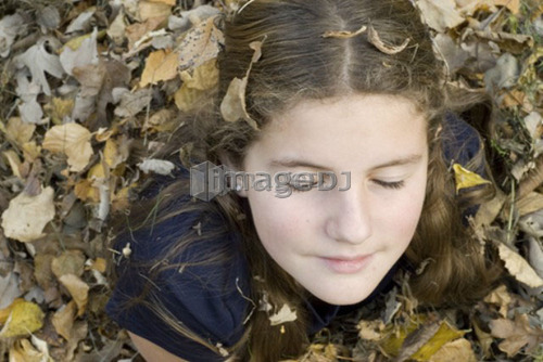 Teen girl covered in leaves, Winnipeg, Canada