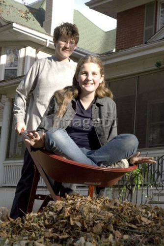Teen brother carrying sister in wheelbarrow, Winnipeg, Canada